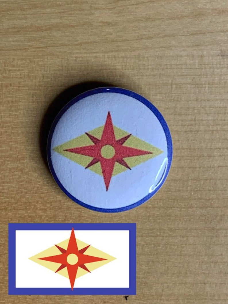 May include: A blue and white button with a red and yellow starburst design. The starburst has a yellow diamond shape with a red star in the center. The star has a yellow circle in the center.