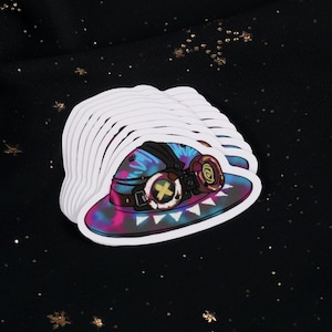 Puede incluir: Una pila de pegatinas con un diseño de sombrero colorido. El sombrero tiene un patrón de teñido anudado con gafas y un cinturón. Las pegatinas son blancas con una forma troquelada, y el fondo es negro con estrellas doradas.