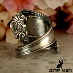Puede incluir: Un anillo de plata hecho de una cuchara, con detalles ornamentados. El anillo presenta un dise&ntilde;o floral decorativo en el cuenco de la cuchara y una banda curvada. Una joya &uacute;nica.