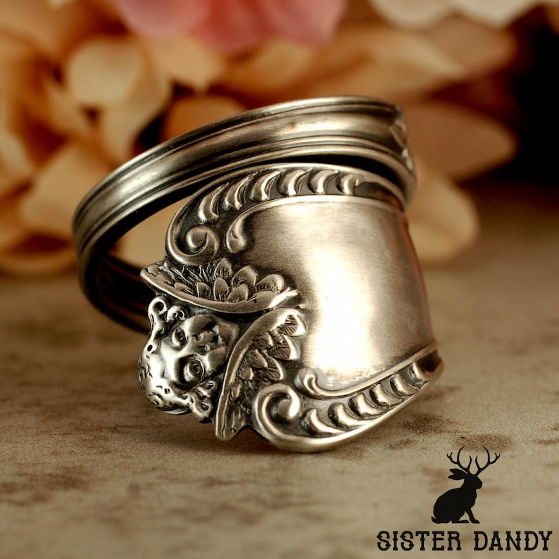 Puede incluir: Anillo de plata hecho con una cuchara, con detalles florales y de rostro ornamentales. El anillo est&aacute; hecho de una cuchara reutilizada, con la cuchara formando la cara del anillo. Una joya &uacute;nica.