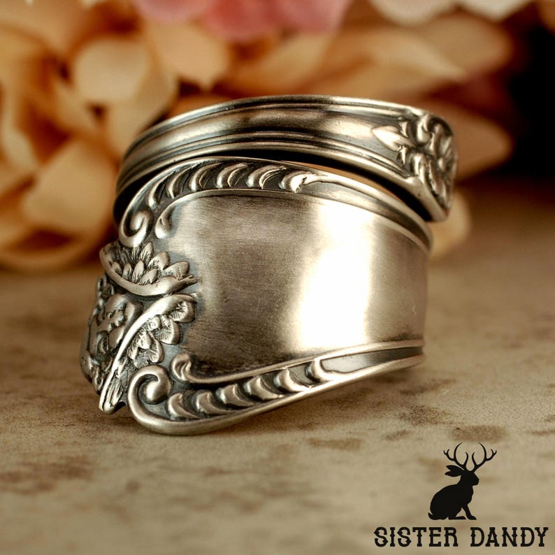 Puede incluir: Un anillo de plata hecho con una cuchara, con detalles florales y de volutas. El anillo, hecho de cubiertos reciclados, tiene una banda ancha. Una joya &uacute;nica.