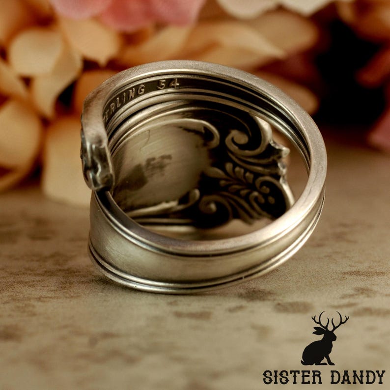 Puede incluir: Anillo de plata hecho a mano a partir de una cuchara, con intrincados detalles florales. El anillo est&aacute; estampado con "STERLING 54" y tiene una est&eacute;tica vintage &uacute;nica. Una pieza de joyer&iacute;a.