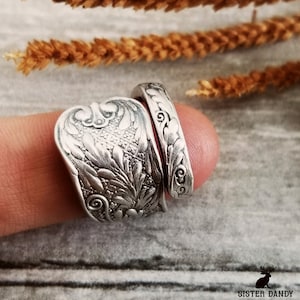 Könnte beinhalten: Zwei silberne Ringe mit filigranen Blumendesigns. Die Ringe werden an einem Finger getragen.