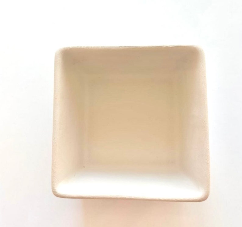 May include: A white ceramic square dish with a smooth, slightly textured surface. The dish is empty and ready to be used for serving or decorating.