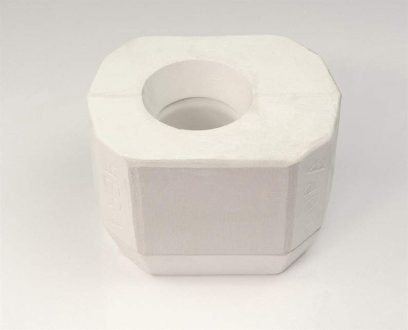 Pode incluir: Forma de cer&acirc;mica branca com uma abertura redonda no centro. A forma tem uma superf&iacute;cie texturizada e &eacute; projetada para artesanato.
