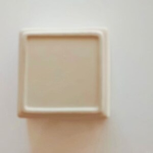 May include: A white ceramic square dish with a raised rim.