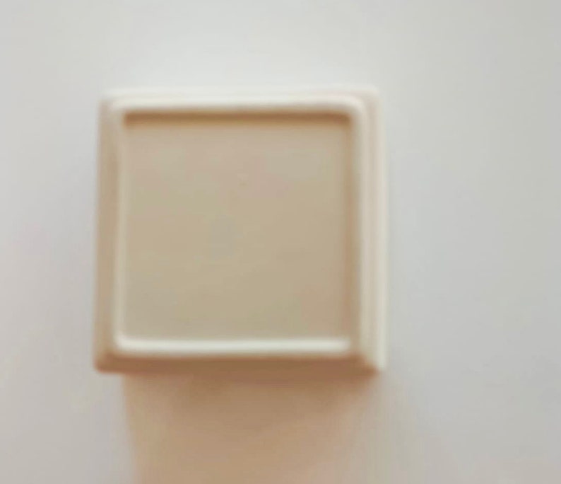 May include: A white ceramic square dish with a raised rim.