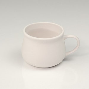 Pode incluir: Uma caneca de cer&acirc;mica branca com corpo arredondado e al&ccedil;a. A caneca est&aacute; vazia e pronta para ser preenchida com sua bebida favorita.