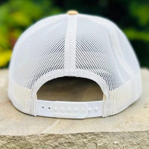 Puede incluir: Gorra de camionero de malla blanca con visera de color canela y una correa ajustable blanca con la palabra "Richardson" impresa.