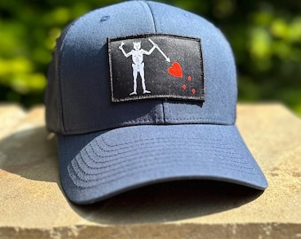 Parche de Blackbeard negro y gorra estilo camionero azul marino con cierre ajustable de Concord & Lex.