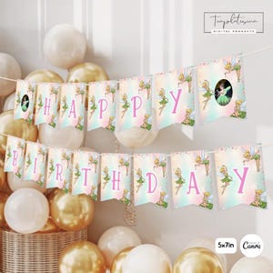 May include: A birthday banner featuring Tinker Bell illustrations on pastel gradient pennants with pink lettering spelling Happy Birthday. The banner includes a circular photo placeholder and is displayed against a background of gold and white balloons.