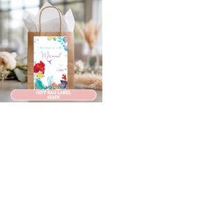 May include: A brown paper gift bag with a white tissue paper lining. The bag features a rectangular label with a mermaid illustration and the text "A little treasure for a little Mermaid". The label is 5x8 inches.