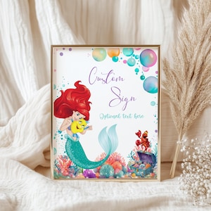 May include: A framed custom sign featuring a mermaid illustration with the text "Custom Sign" and "Optional text here." The artwork includes colorful bubbles and coral reef elements, with a gold frame.