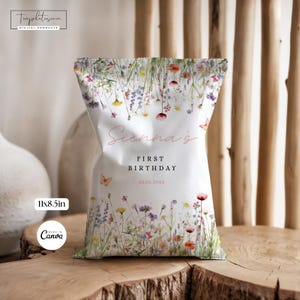 Puede incluir: Bolsa de recuerdo de fiesta blanca con un diseño floral con flores silvestres en tonos rosa, amarillo y morado. La bolsa lleva la inscripción "Sienna's First Birthday" con la fecha 20.06.20xx. La bolsa mide 27,9 x 21,6 cm.