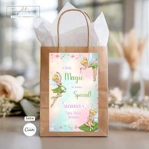 May include: A brown paper gift bag with a white tissue paper lining. The front features a colorful design with fairy illustrations and the text "A Little Magic for Sienna's Fairy Third Birthday". The bag measures 5x8 inches.