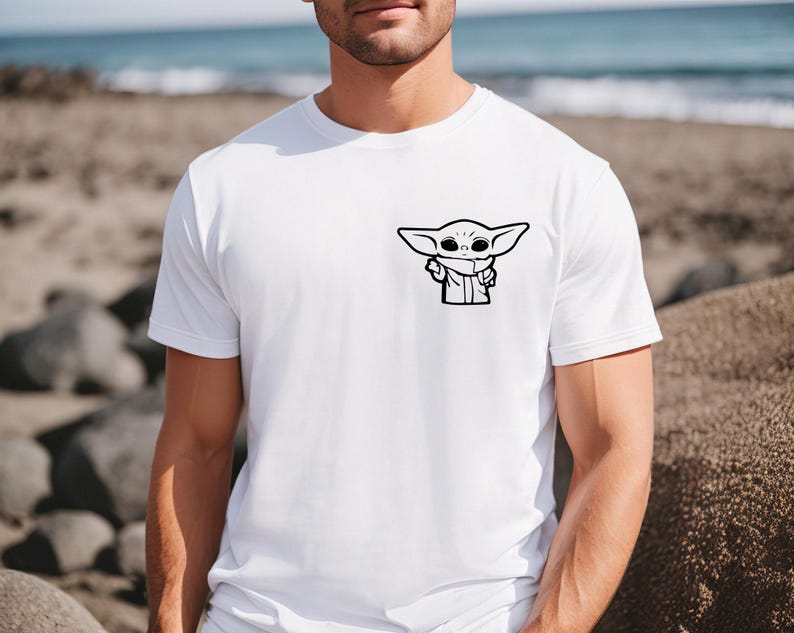 May include: A white t-shirt with a black and white cartoon image of a character from the Star Wars franchise, The Mandalorian, known as "Baby Yoda".