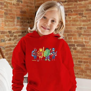 May include: A red hooded sweatshirt featuring a colorful graphic of several superheroes, including Spider-Man, Iron Man, Hulk, and Captain America. The sweatshirt is worn by a young person with blonde hair.