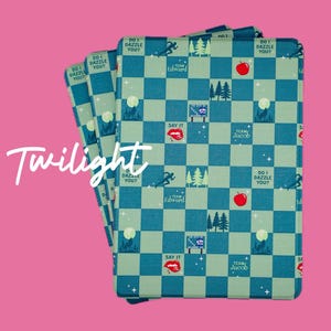 May include: A stack of four blue and green playing cards with a checkered pattern. The cards feature images of a wolf, a red apple, a running figure, and text that says "Do I Dazzle You?" and "Team Edward" and "Team Jacob".