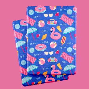 May include: Two blue notebooks with a summer-themed pattern featuring pink flamingos, beach balls, sunglasses, and donuts. The notebooks are stacked on a pink background, creating a vibrant and playful design.