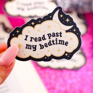 May include: A white sticker with a black outline in the shape of a cloud with a crescent moon and stars. The text on the sticker reads "I read past my bedtime".