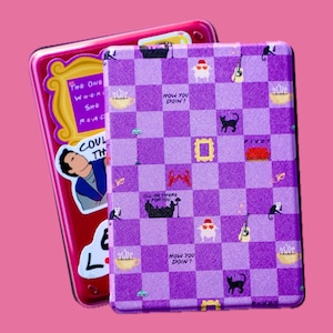 May include: Purple and white checkered phone case with a Friends TV show theme. The case features various icons from the show, including the iconic orange couch, a coffee cup, and the words "How You Doin't".