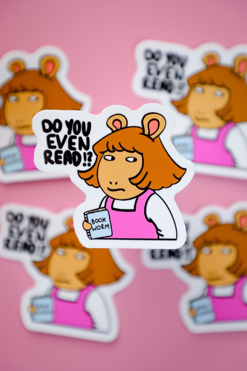 May include: A sticker featuring a cartoon character with orange hair and a pink dress, holding a book labeled "Book Worm." The text "DO YOU EVEN READ?!" is above the character. The background is pink.