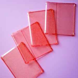 May include: Five pink glitter phone cases stacked on top of each other on a light purple background.
