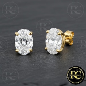 May include: A pair of oval-cut diamond stud earrings set in gold. The diamonds are clear and sparkling, with a brilliant cut. The earrings have a classic, elegant design, perfect for everyday wear or special occasions.