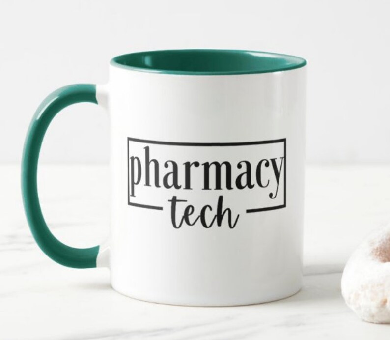 Pu&ograve; includere: Tazza da caff&egrave; in ceramica bianca con bordo e manico verde acqua. La tazza ha la scritta "pharmacy tech" stampata in nero sul davanti.