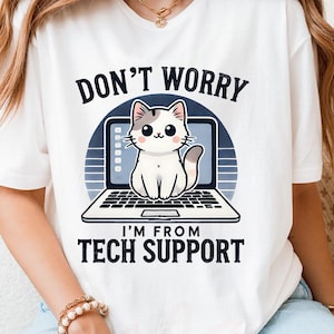 May include: White t-shirt featuring a cartoon cat sitting on a laptop. The text "DON'T WORRY I'M FROM TECH SUPPORT" is printed above and below the cat illustration. The shirt is a casual wear item.