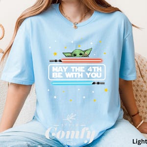 K&ouml;nnte beinhalten: Hellblaues T-Shirt mit einem Cartoon-Bild eines gr&uuml;nen Au&szlig;erirdischen mit dem Text "M&ouml;ge der 4. Mai mit dir sein".