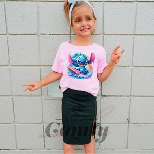 a little girl wearing a pink shirt and black skirt