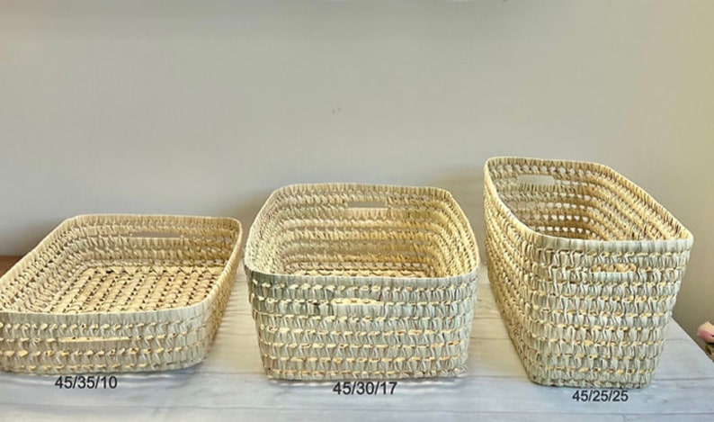 Puede incluir: Tres cestas tejidas de diferentes tama&ntilde;os. Las cestas est&aacute;n hechas de materiales naturales y tienen un color beige claro. Las cestas est&aacute;n etiquetadas con sus dimensiones: 45/35/10, 45/30/17 y 45/25/25.