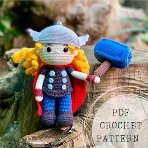 Può includere: Schema all'uncinetto per una graziosa bambola Thor in stile cartone animato con un mantello rosso e un martello blu. Lo schema è disponibile per il download in PDF.