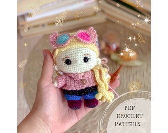 Może przedstawiać: Wzór na szydełku na różową i żółtą lalkę amigurumi z okularami i różdżką. Lalka ma na sobie różowy sweter, niebieskie dżinsy i fioletowe buty. Wzór dostępny jest jako plik PDF do pobrania.  PDF CROCHET PATTERN