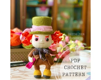 Puede incluir: Patrón de crochet para un amigurumi del Sombrerero Loco. La muñeca lleva un sombrero verde con una banda rosa, una chaqueta marrón y zapatos amarillos. La muñeca tiene el pelo rojo y una cara blanca con rasgos pintados.