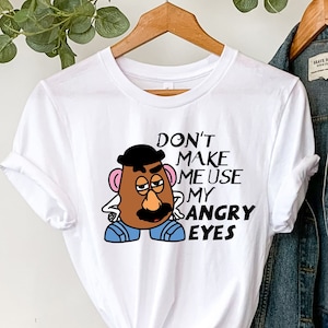 May include: White t-shirt featuring a cartoon image of Mr. Potato Head with the text "Don't make me use my angry eyes."