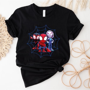 May include: Black t-shirt with a graphic of three cartoon Spider-Man characters in a web. The characters are red, black, and white.