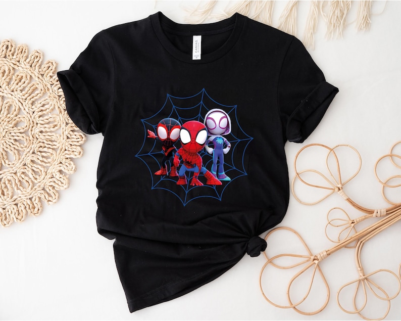 May include: Black t-shirt with a graphic of three cartoon Spider-Man characters in a web. The characters are red, black, and white.