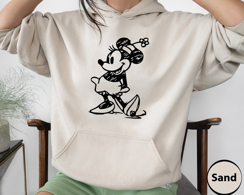 Puede incluir: Una sudadera con capucha de color arena con una ilustraci&oacute;n en blanco y negro de Mickey Mouse en la parte delantera. La ilustraci&oacute;n es un dibujo de estilo vintage de Mickey Mouse.