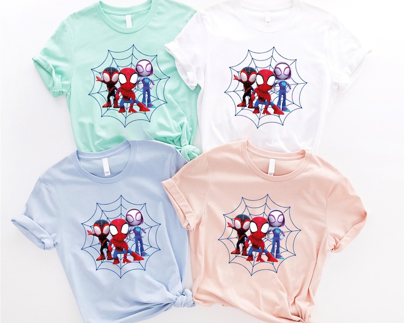 May include: Four t-shirts with a graphic print of three cartoon Spider-Man characters standing on a web. The shirts are in different colors: light blue, light green, white, and pink.