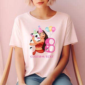 Pu&ograve; includere: Maglietta rosa con un'immagine di cartone animato di una ragazza con un maiale e un numero 8 rosa. Il testo "CUSTOM TEXT" &egrave; stampato sotto l'immagine.
