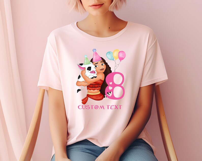 Pu&ograve; includere: Maglietta rosa con un'immagine di cartone animato di una ragazza con un maiale e un numero 8 rosa. Il testo "CUSTOM TEXT" &egrave; stampato sotto l'immagine.