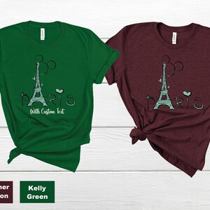Op de afbeelding: Twee T-shirts, &eacute;&eacute;n in Kelly Green en &eacute;&eacute;n in Heather Maroon, elk met een afbeelding van de Eiffeltoren en het woord "PARIS". Het ontwerp bevat een hart en de tekst "With Custom Text".