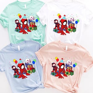 Puede incluir: Cuatro camisetas de diferentes colores con una imagen de dibujos animados de Spider-Man y Spider-Gwen celebrando un cumplea&ntilde;os con regalos y globos.