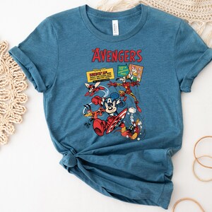 May include: A blue t-shirt with a graphic of Disney characters as The Avengers. The design includes Mickey Mouse, Donald Duck, Iron Man, and Thor. The word "AVENGERS" is printed in red at the top.