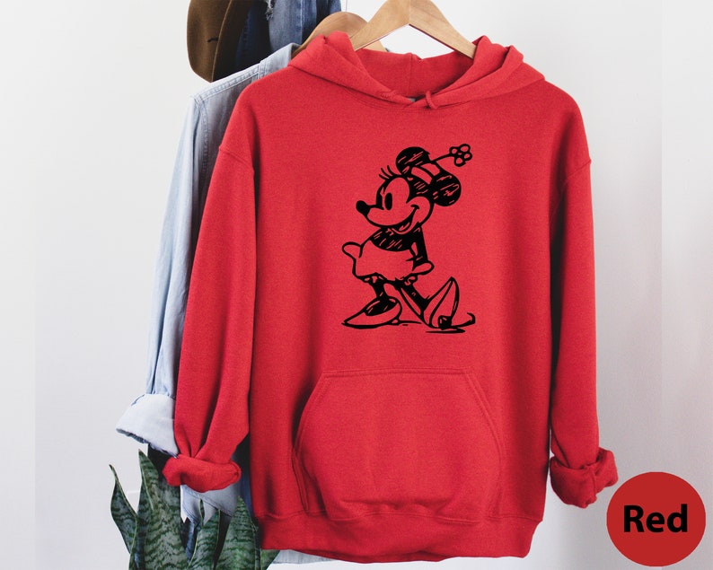Puede incluir: Sudadera con capucha roja con una ilustraci&oacute;n en blanco y negro de Minnie Mouse con un sombrero y una falda.