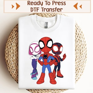 May include: White t-shirt featuring a DTF transfer of three cartoon Spider-Man characters. The characters are Spider-Man, Spider-Gwen, and Miles Morales. The characters are in a superhero pose.