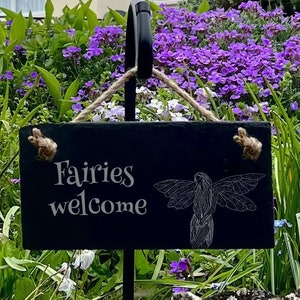May include: Black slate garden sign with the text "Fairies welcome" and a white silhouette of a fairy with wings.