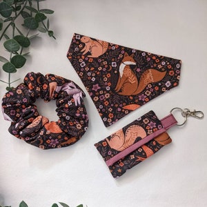 May include: A set of three items featuring a fox and floral pattern. The set includes a scrunchie, a bandana, and a key chain.